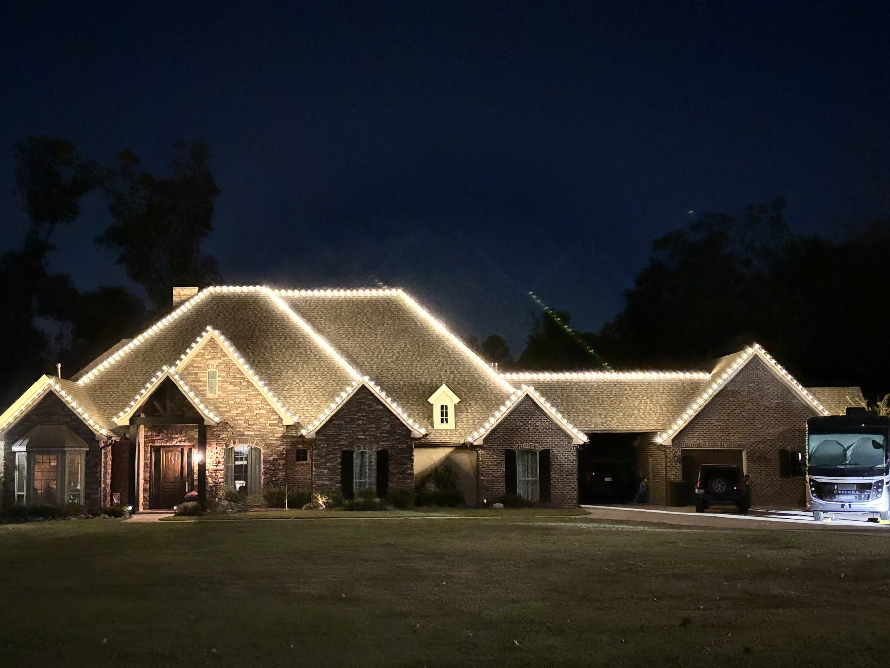 Brick home with a warm white C9 roofline across every gable at night