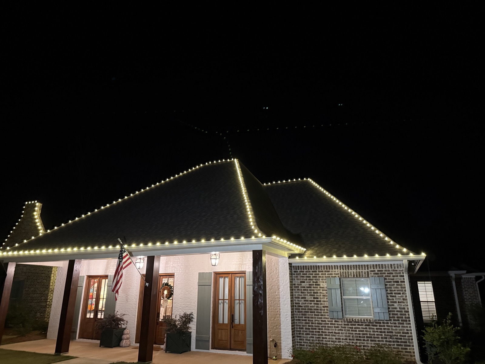 Crisp warm white C9 roofline across a brick home's hips and gables