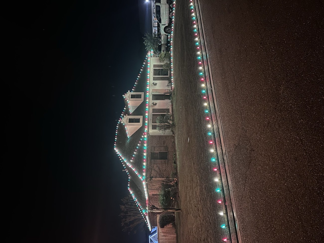 House with a multicolor roofline and a matching lit line along the yard
